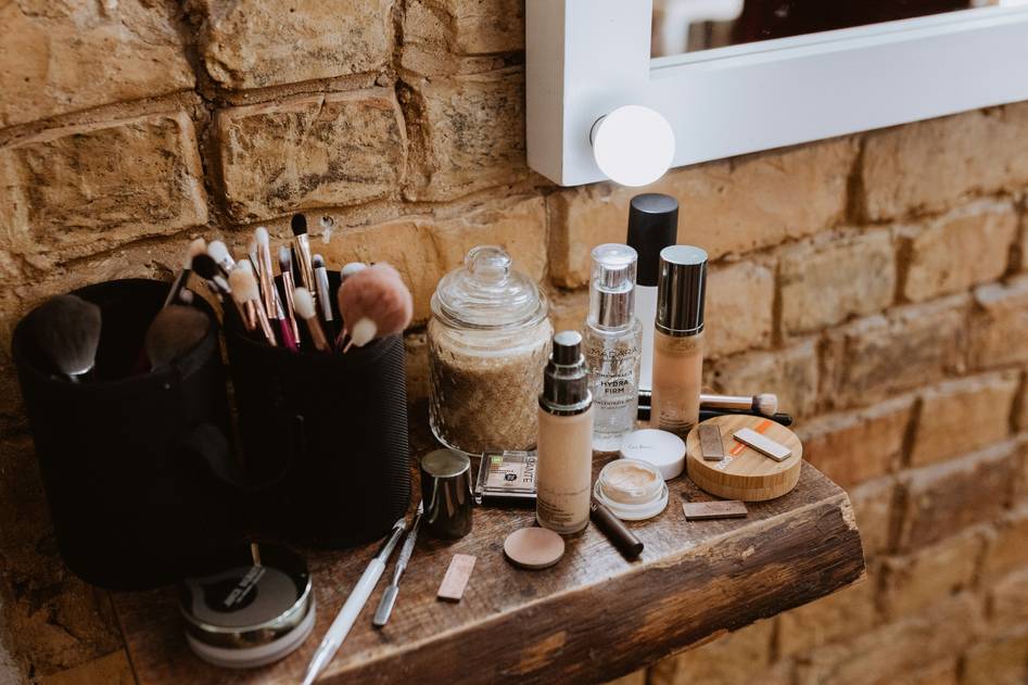 Close-up of hands organizing makeup brushes inside a designer makeup bag on a soft pink backdrop